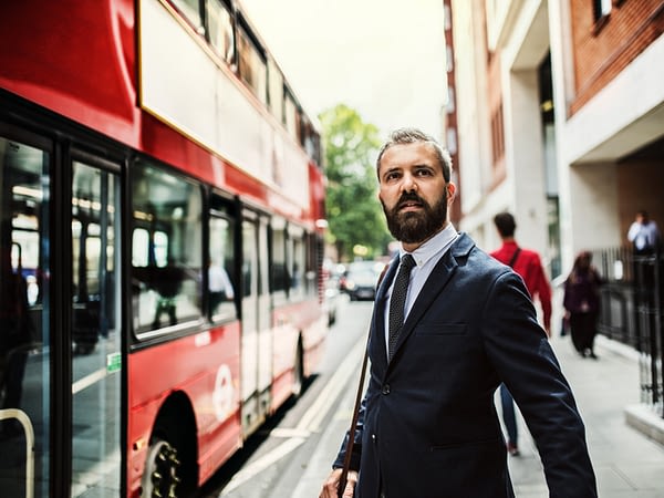 Hipster businessman standing on the street, waiting for the bus in London.